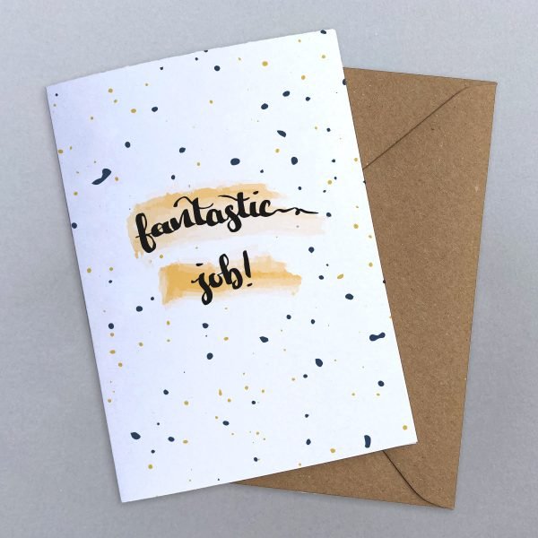 Congratulations card with fantastic job written in calligraphy on top of an orange watercolour swipe on a black splattered background