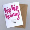 A hand calligraphy greeting card with hip hip hooray it's your birthday in pink on a white background