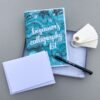 Black pen kit contents: calligraphy workbook, 2 blank greeting cards, 10 blank gift tags, and a black Tombow fude pen all in a grey gift box