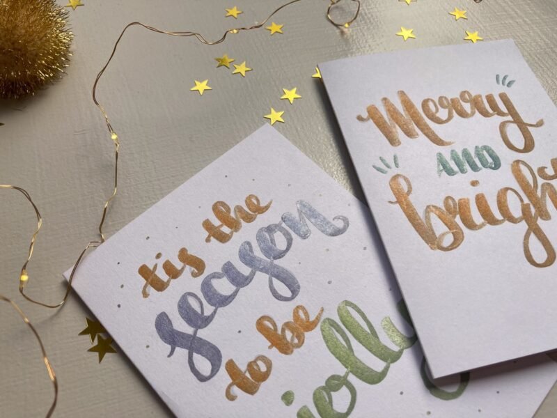 Close up of hand-lettered Christmas cards created with metallic pens
