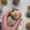 holly jolly gold bauble with pink hand drawn decoration